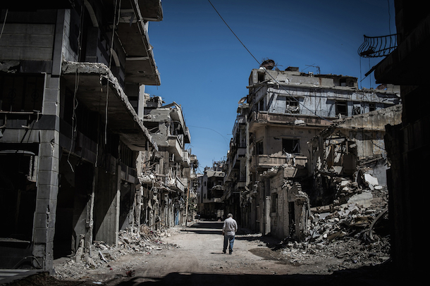 A Syrian refugee walks among severely damaged buildings in downtown Homs, Syria, on June 3, 2014. (Pan Chaoyue/Xinhua)