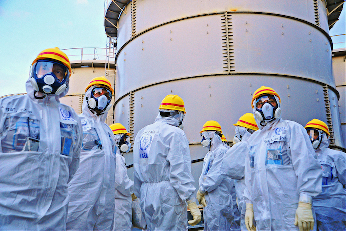 IAEA inspectors stand in front of water tanks at the Fukushima nuclear plant in 2013
