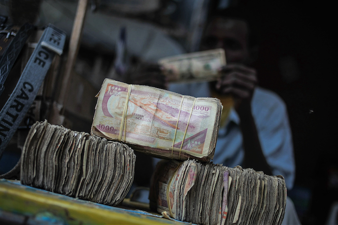 A Somali money exchanger inspects a $10 dollar bill on the streets of the Somali capital Mogadishu