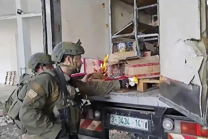 Israeli troops being filmed trying to burn food and water supplies in the back of an abandoned truck in Gaza