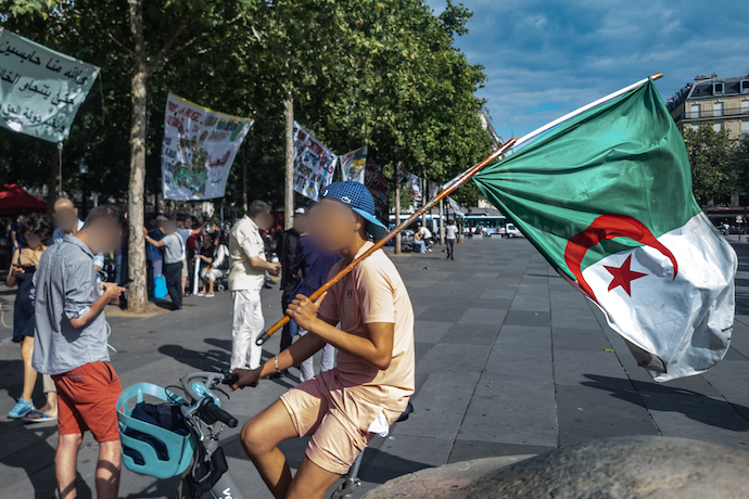 A bicyclist holds an Algerian flag during a demonstration in Place de la République